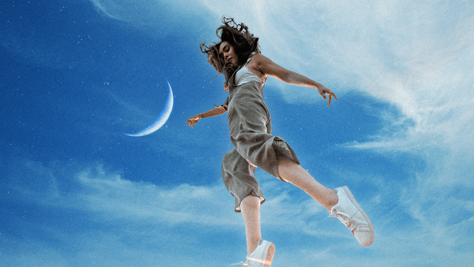 A woman jumping into the sky with a crescent moon behind her