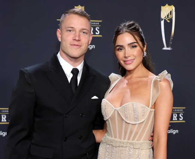 Christian McCaffrey's wife. Christian McCaffrey in a tuxedo and Olivia Culpo is a sheer corset dress in front of a black background.