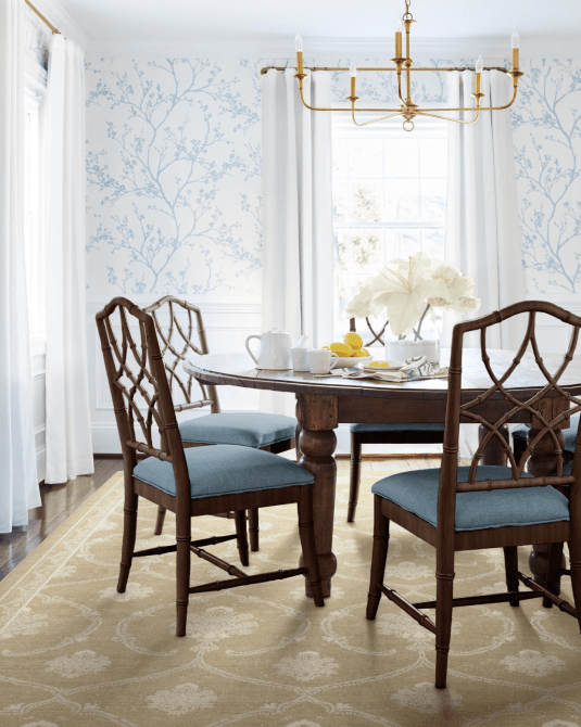 A dining room with traditional furniture and a beige printed rug