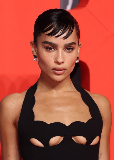 Zoe Kravitz wearing a black dress, she has side swept baby bangs.