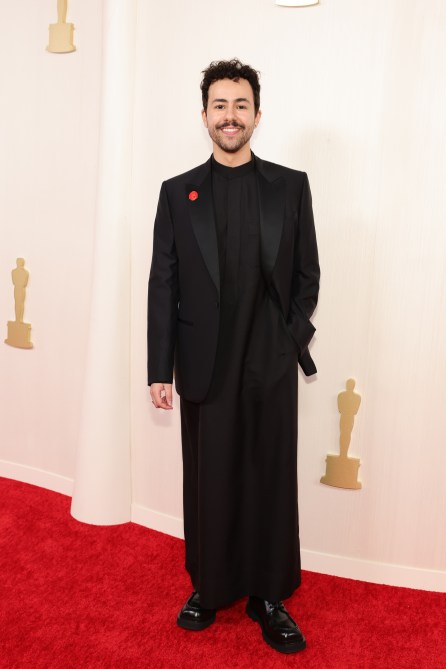 Ramy Youssef at the 2024 Oscars red carpet in a black jumpsuit and black blazer