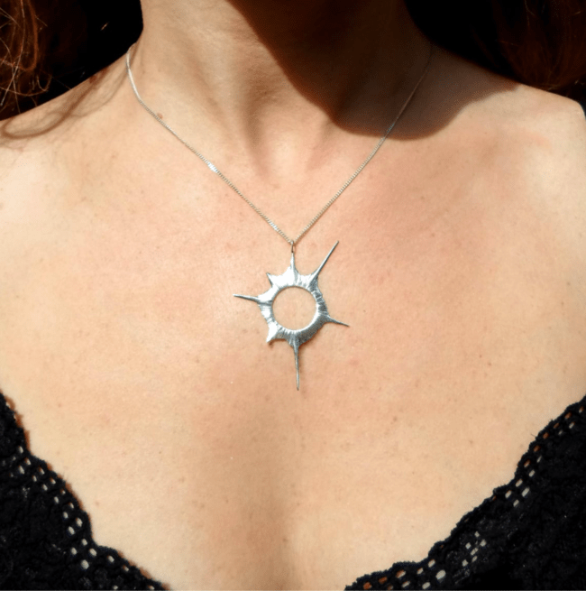 A woman wearing a silver solar eclipse necklace