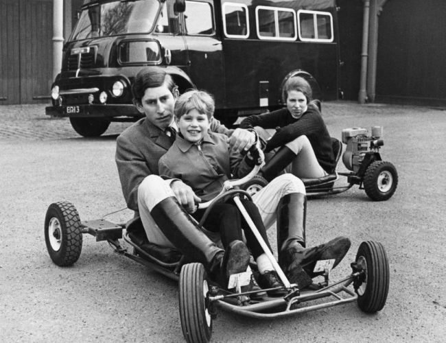 Charles, Prince of Wales and Prince Edward riding together in go-kart while Princess Anne drives behind them.