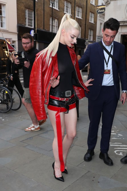 Anya Taylor-Joy wearing a red leather jacket and a skirt made of belts.