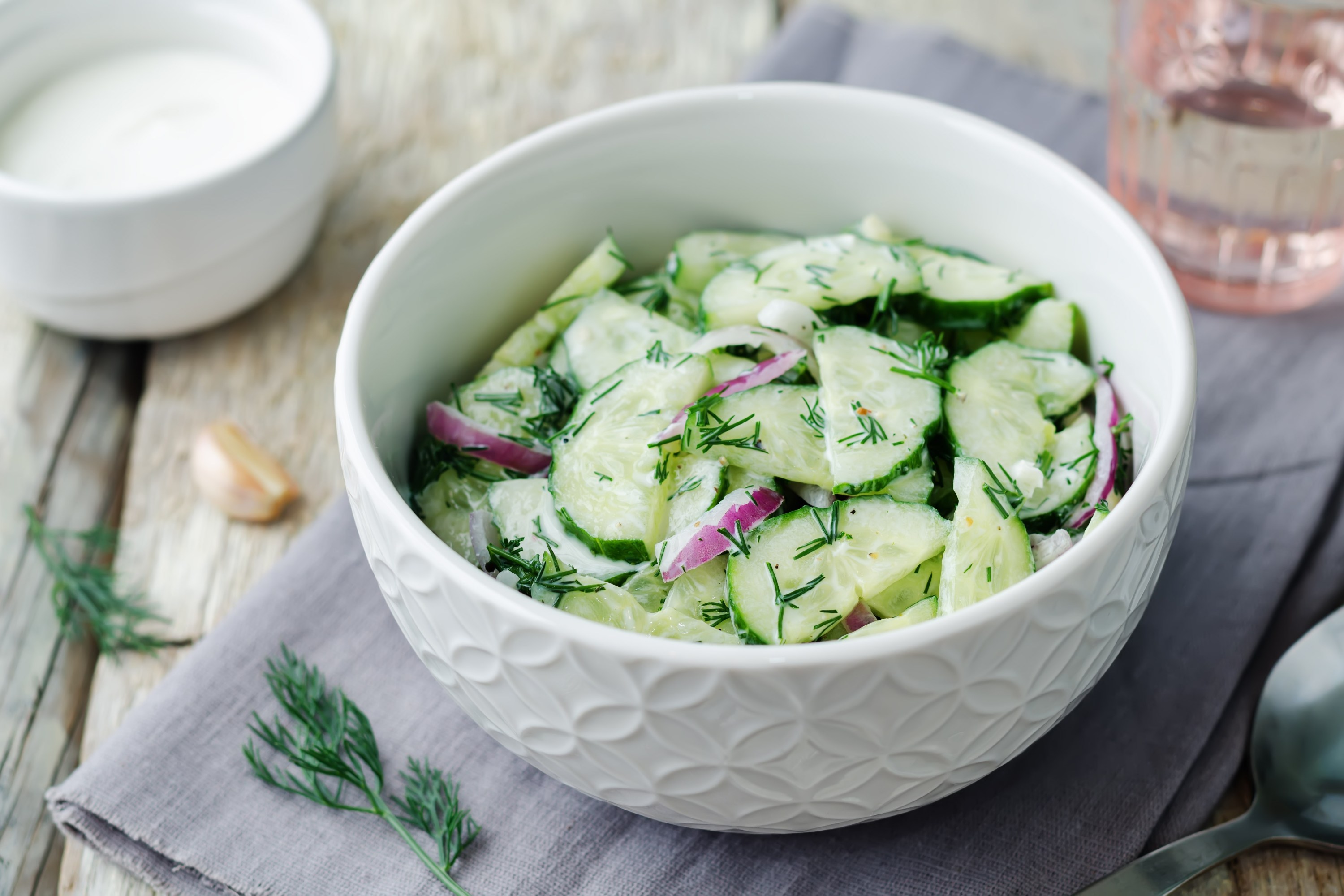 A bowl of cucumber salad with dill and red onion