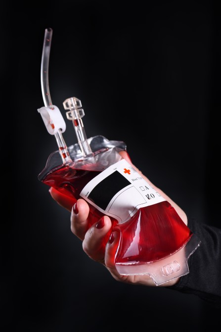 A hand holds a "blood bag" filled with alcohol