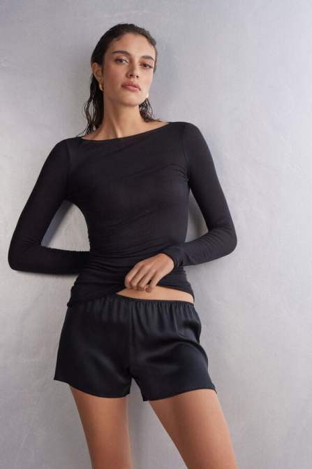 Model wears sheer long sleeve black top.