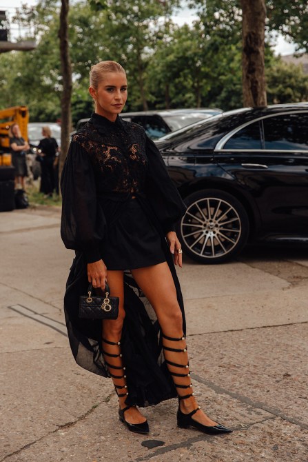 a model wears a lace blouse, a draped skirt, and wrap up ballet flats