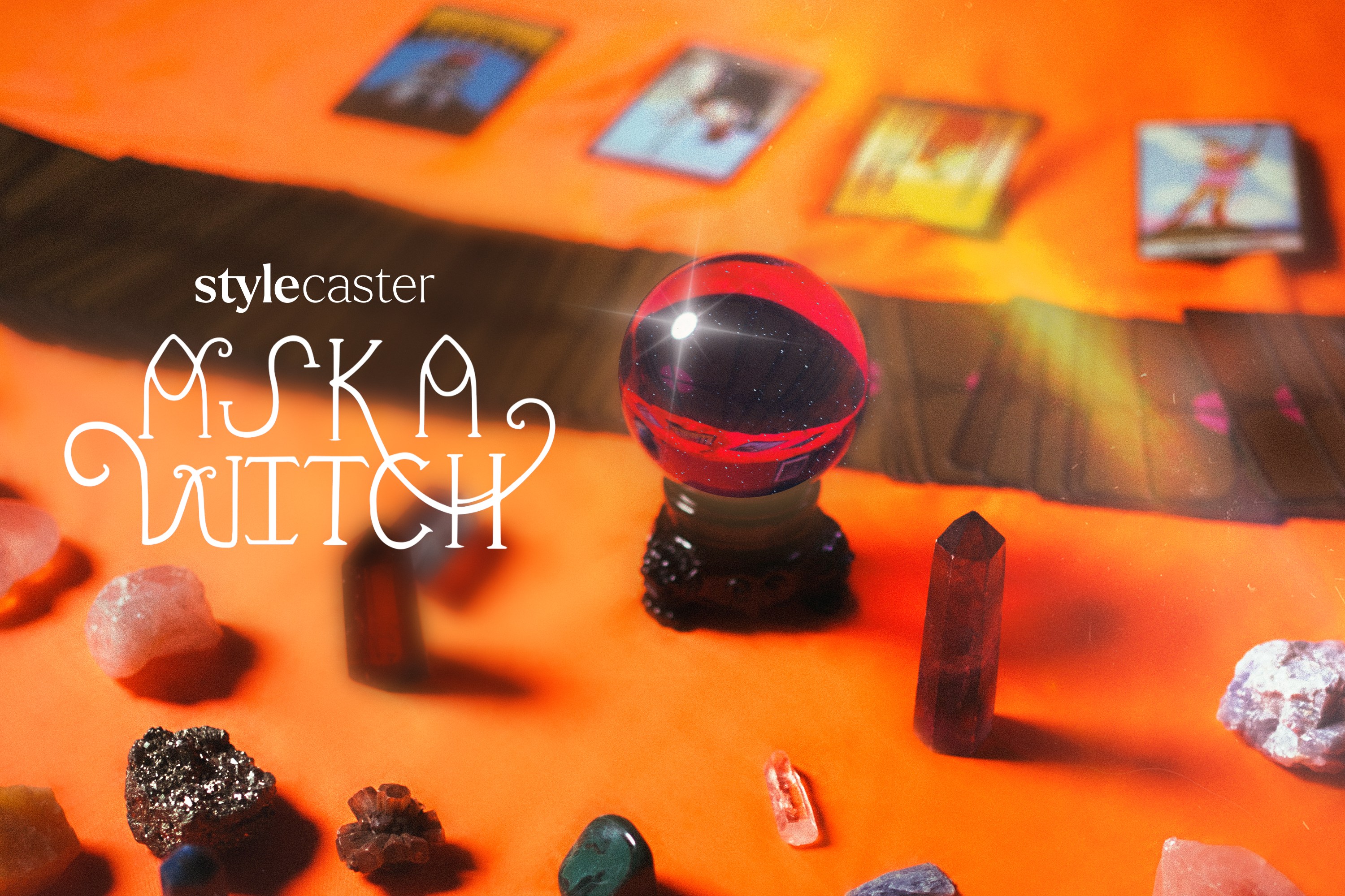 A purple and sparkling crystal ball surrounded by tarot cards and other assorted crystals