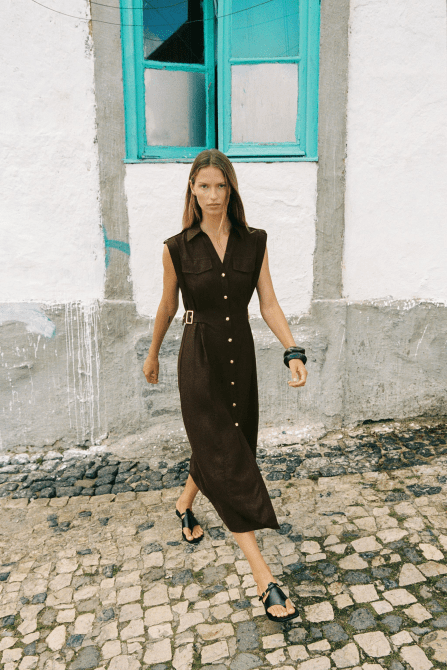 A model walking on the street wearing the Zara Linen Midi Dress in dark brown