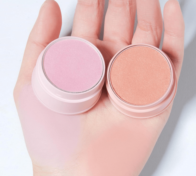 Someone holding and swatching the TONYMOLY Cheek Tone Jelly Blusher in Fog Pink (left) and Nude Amber (right)