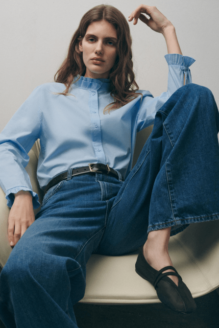A model wearing the Zara Double Strap Mesh Ballet Flats in black with a light blue button-down blouse and dark wash jeans