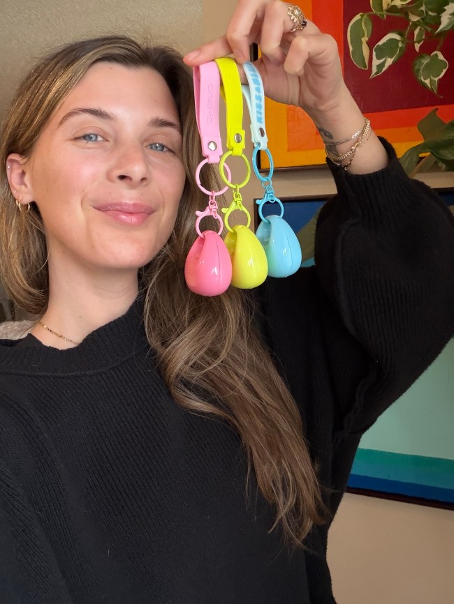 A woman holding the Creme Shop lip and cheek balms in pink, yellow, and blue. 